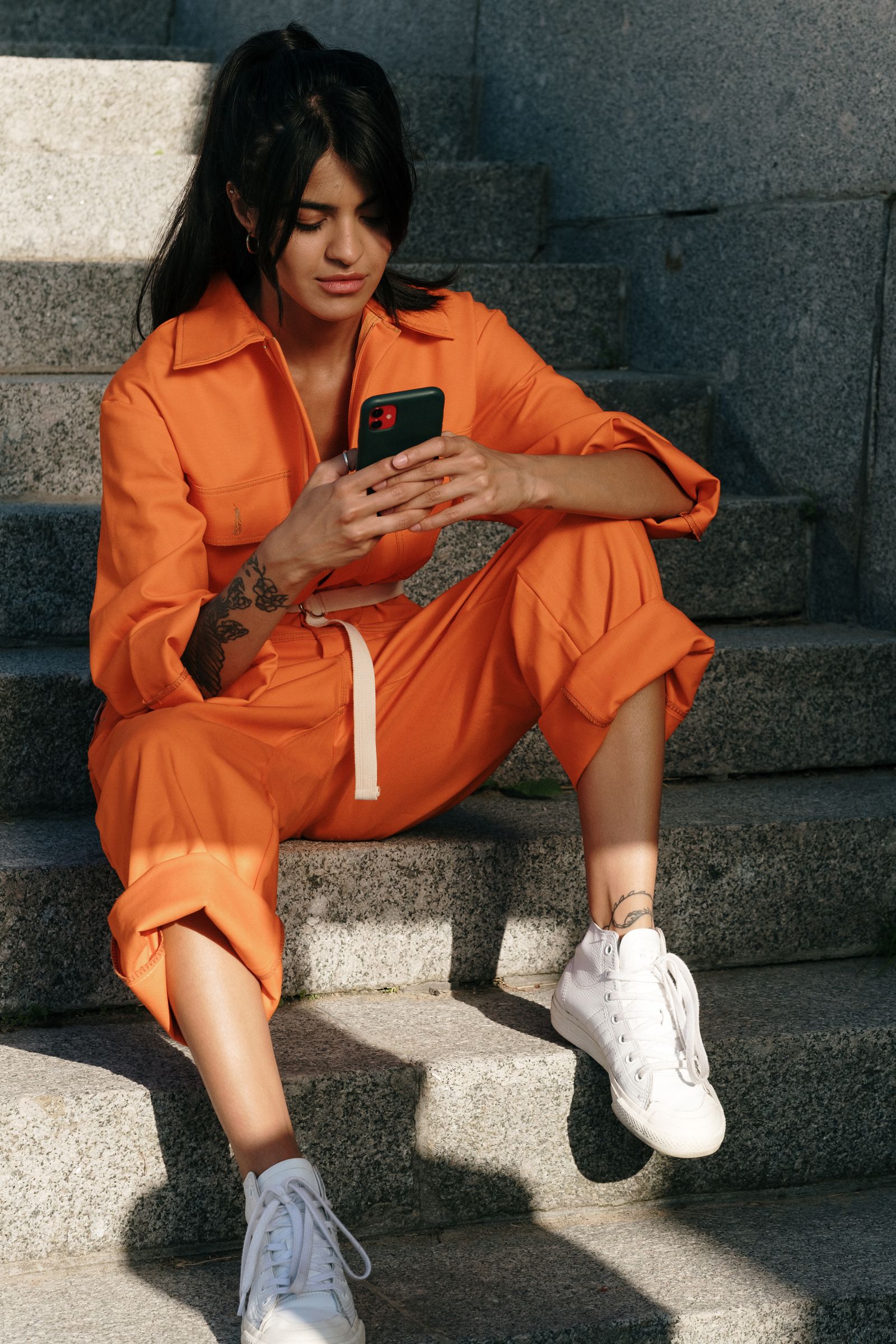 A person in orange using a smartphone outdoors